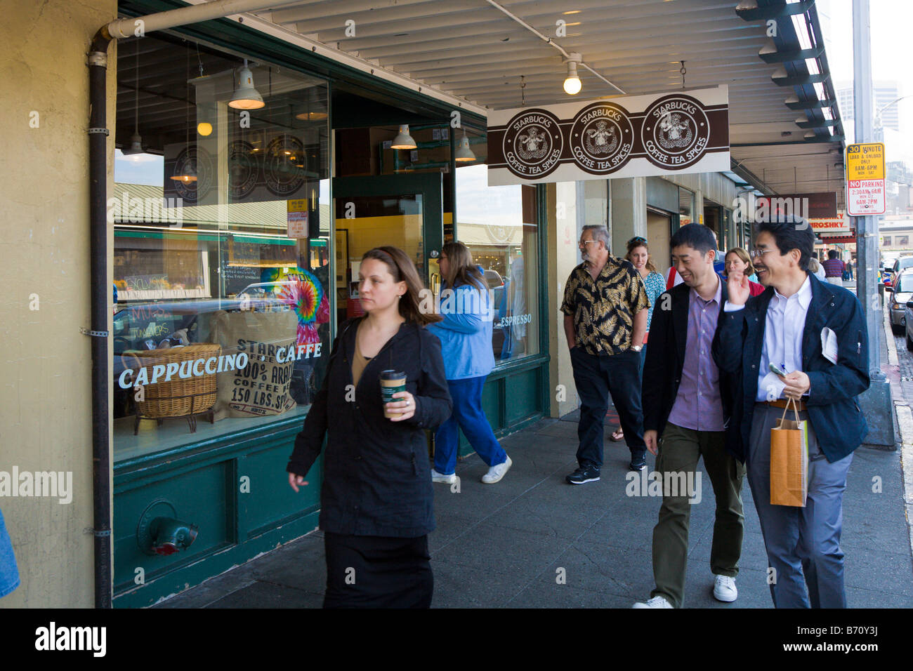 People walking past the exterior of the first original Starbucks coffee shop in Seattle, Washington Stock Photo