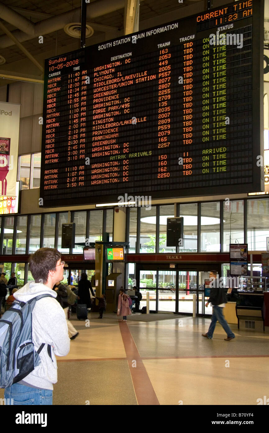 Young man looks at departure schedule board in South Station located in Dewey Square Boston Massachusetts USA Stock Photo