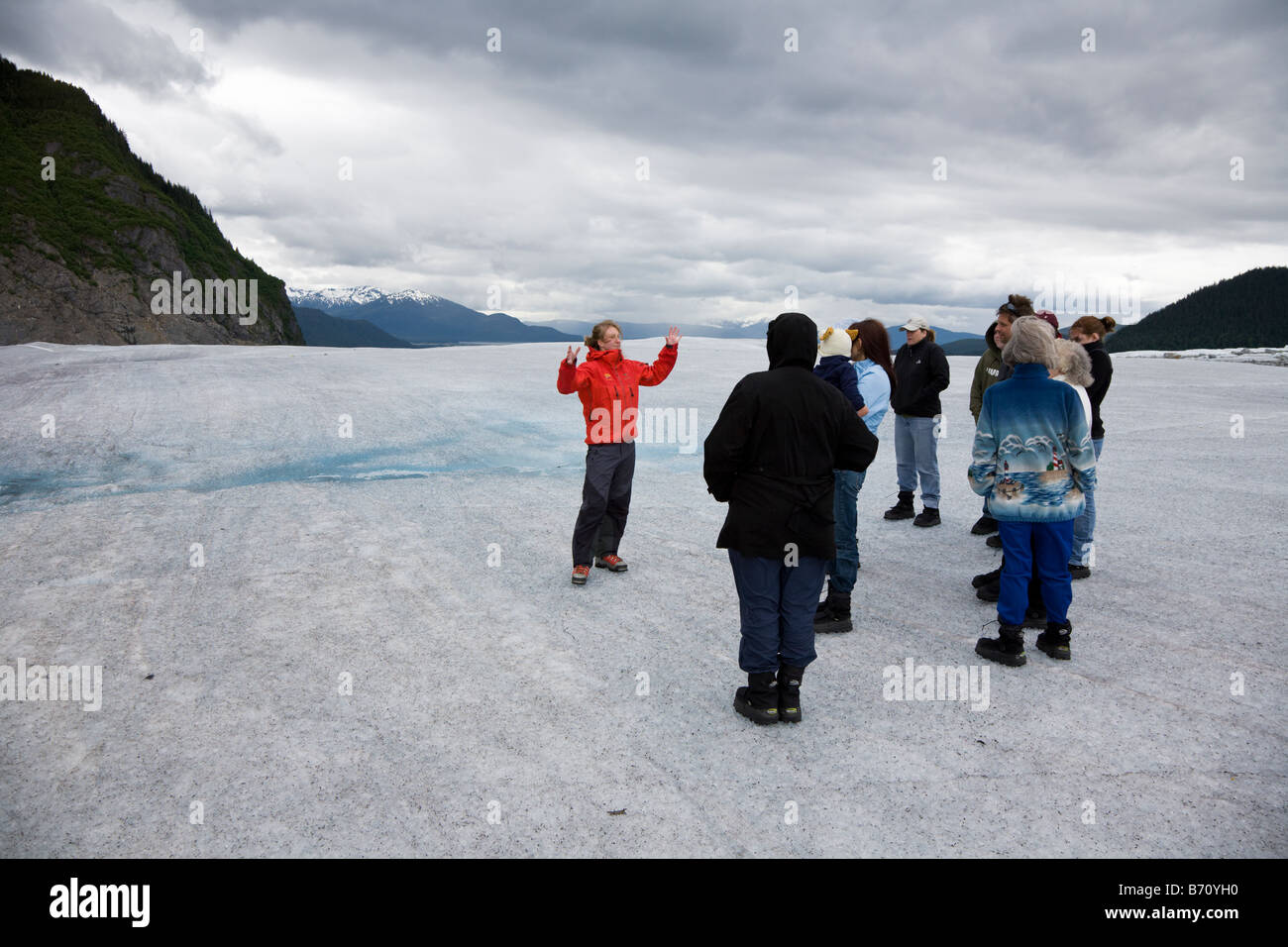 Tour guide on top of Mendenhall Glacier near Juneau Alaska teaches and entertains tourists. Stock Photo