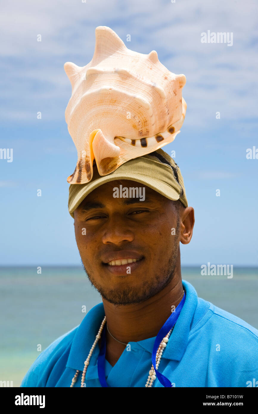 Man on the beach in Mauritius selling large conch shells taken by diving from the Indian Ocean Stock Photo