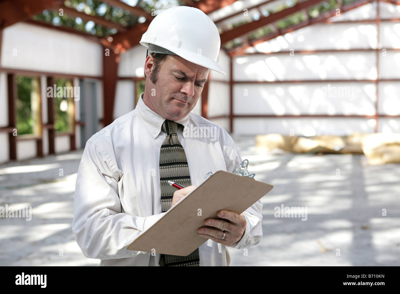 An unhappy looking construction inspector marking his checklist on a ...