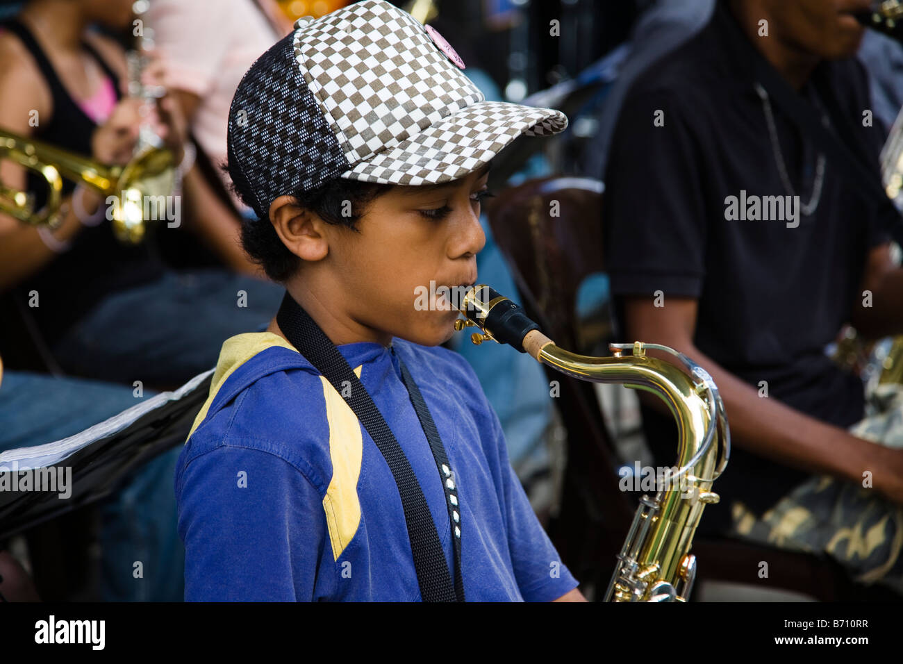 Young boy in Mauritius playing saxophone in street band busking in Port