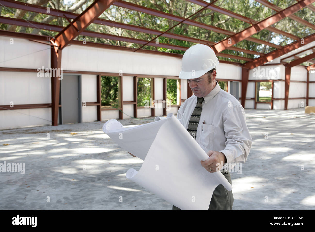 An architect going over blueprints on the jobsite Steel frame ...