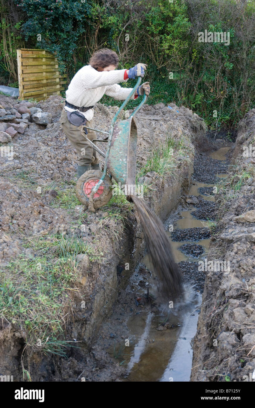 Filling in land drainage trench with gravel prior to laying land-drain pipes Stock Photo