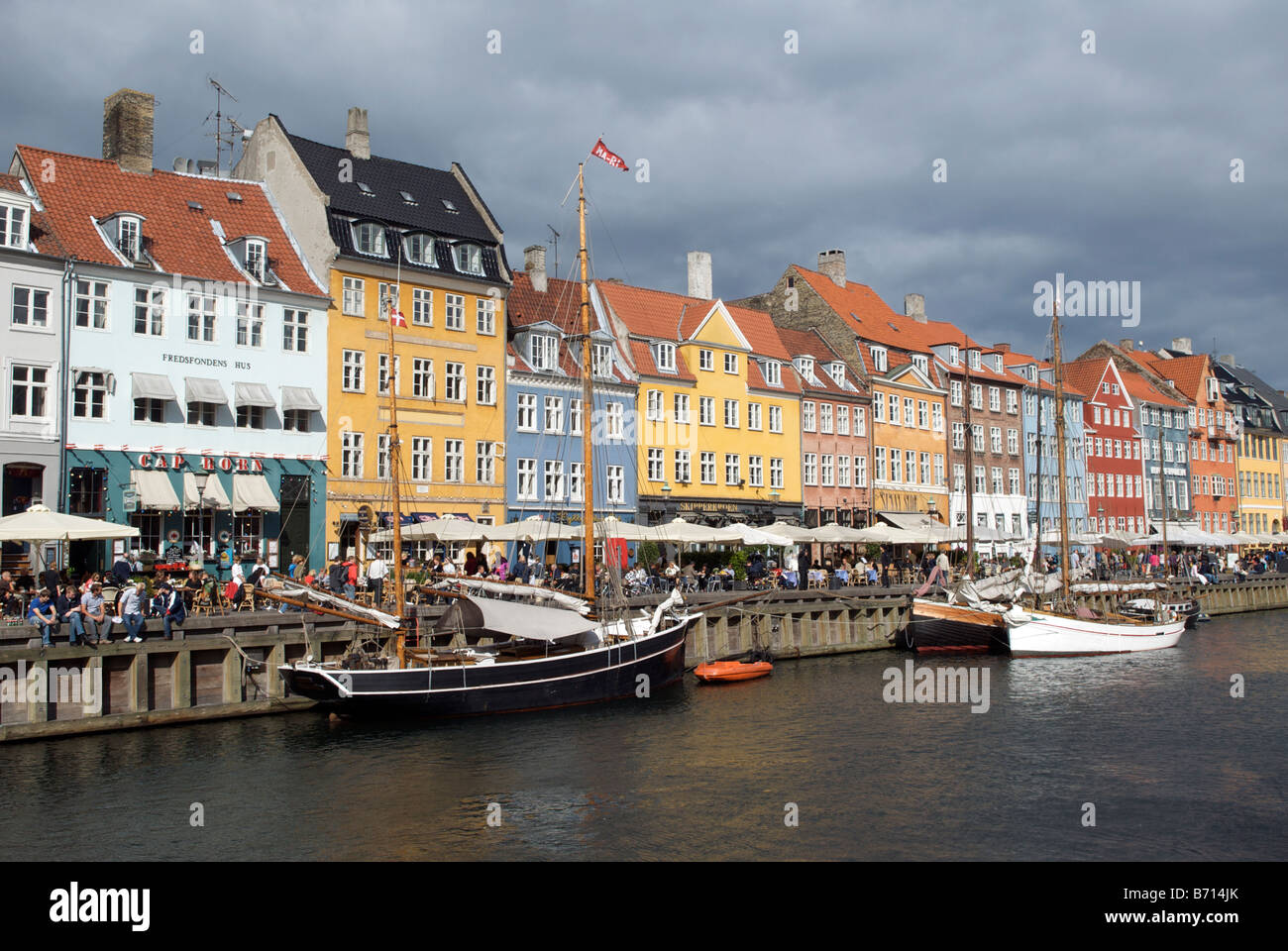 Boats and colourful buildings with waterfront cafes and restaurants Nyhavn Copenhagen Denmark Stock Photo