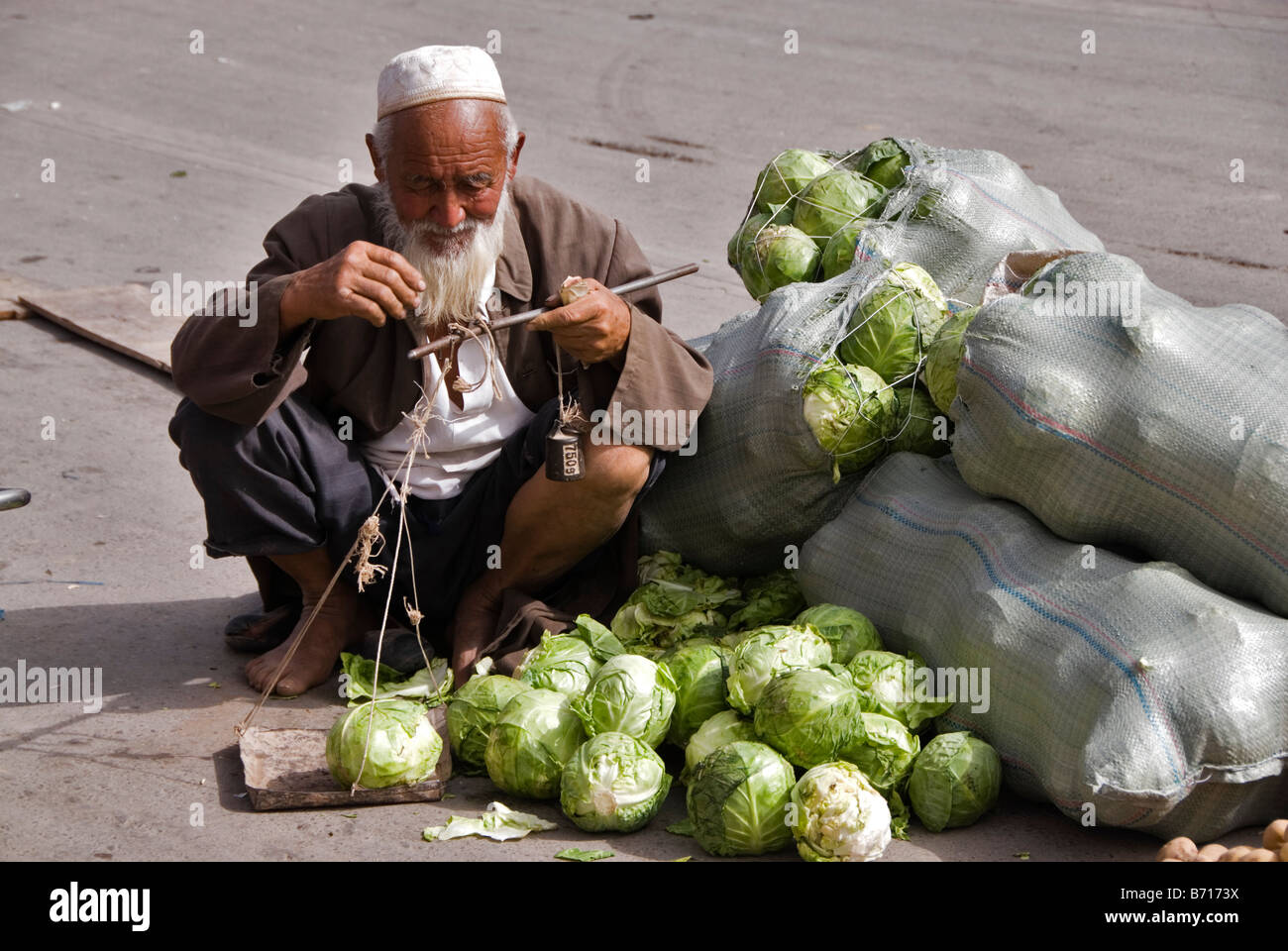 Old man weighing cauliflowers in a market Kashgar Xinjiang China Stock Photo
