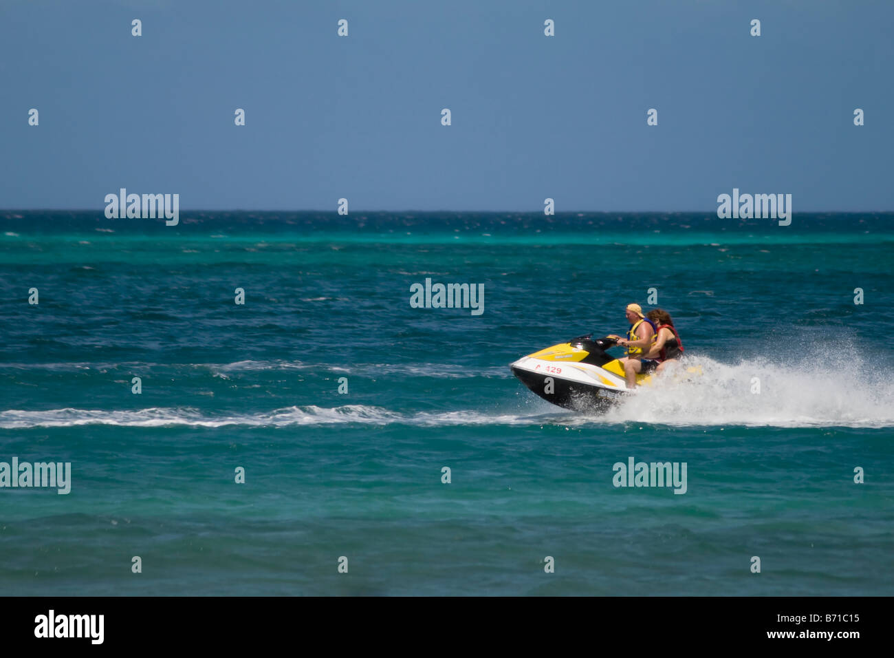 2 people ride a Sea Doo personal watercraft "Jet Ski" in Aruba Stock