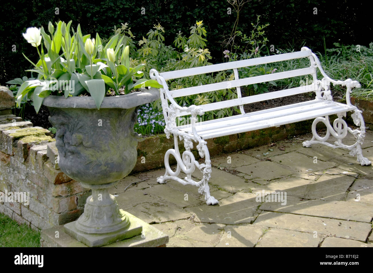 An elegant garden urn and white bench Stock Photo