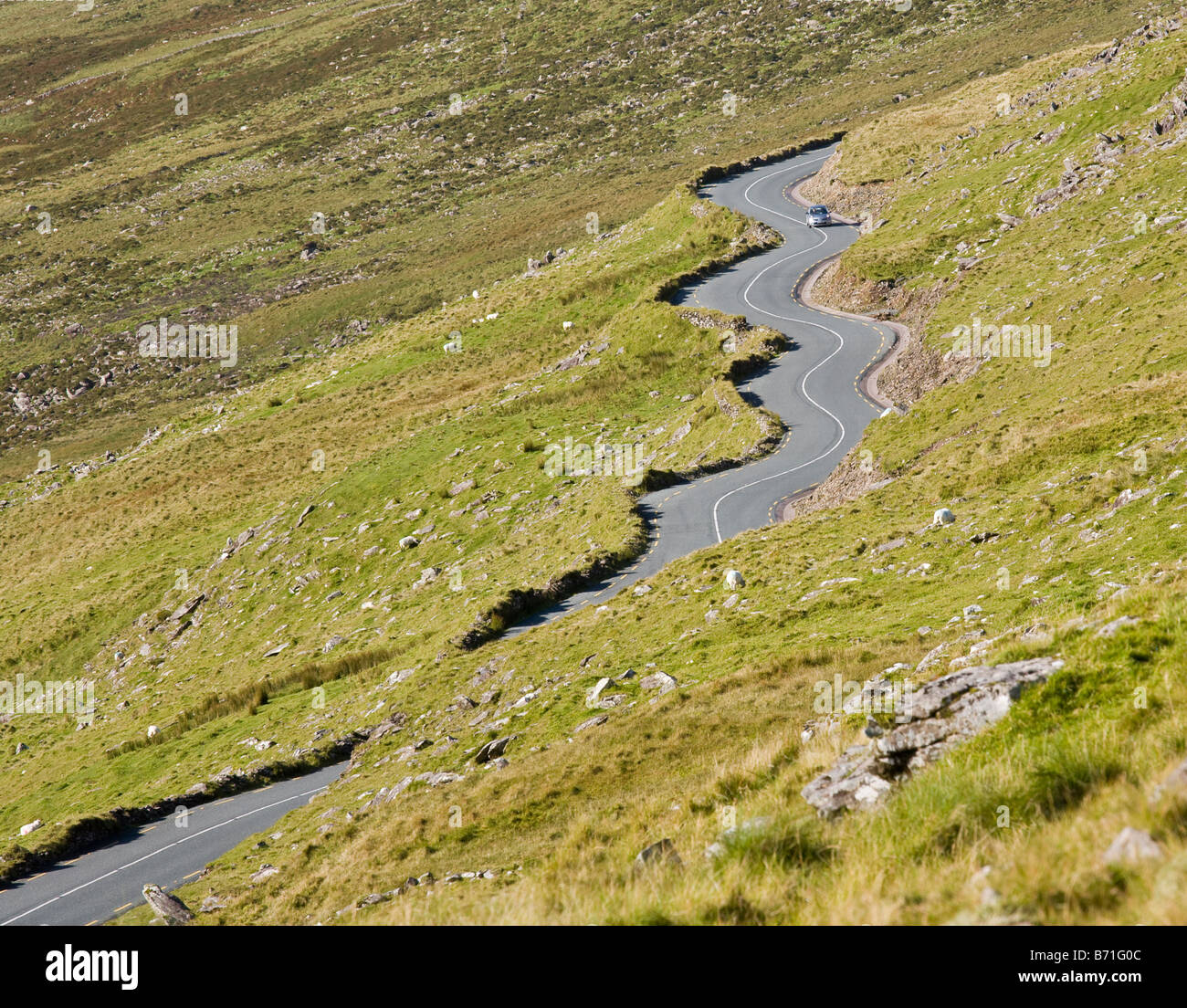 Winding up Connor Pass. A silver car drives up the winding road from Dingle Town Stock Photo