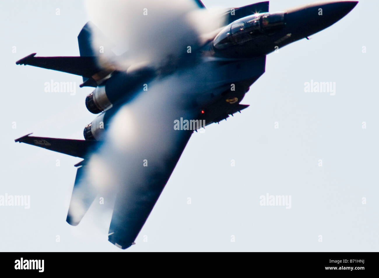 A vapor burst forms on the wings of an F 15 Strike Eagle in a high speed banked turn at low altitude Stock Photo