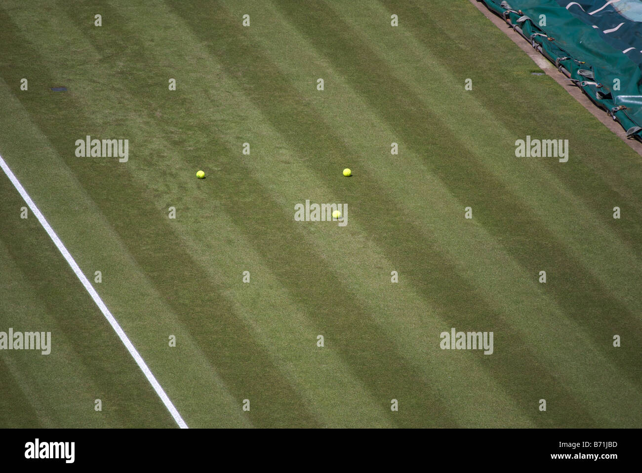 3 tennis balls lay on the grass, waiting for a ball boy to collect them by the side of court number 1, Wimbledon Stock Photo