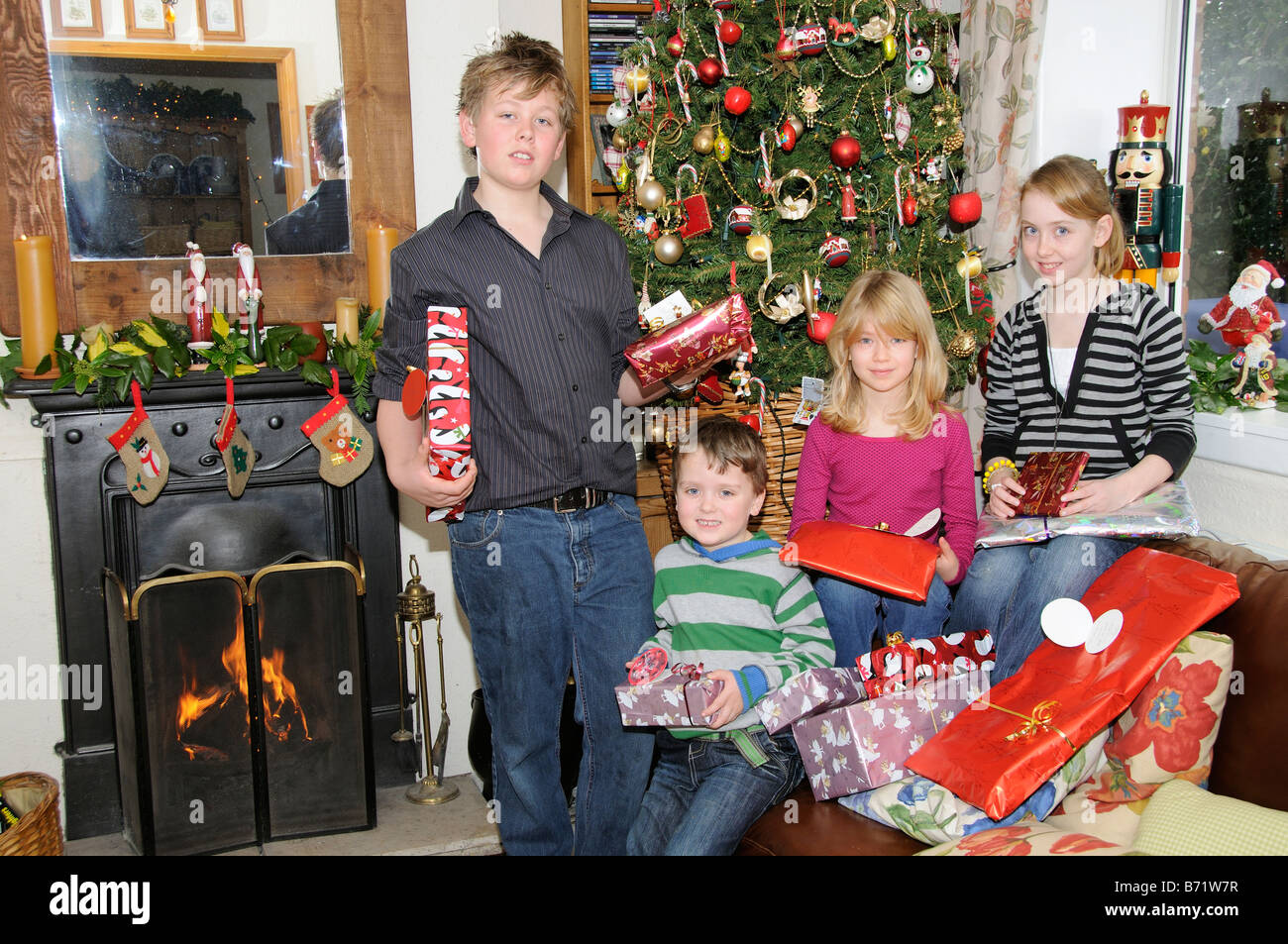 Children around an open fire and decorated Christmas tree opening their