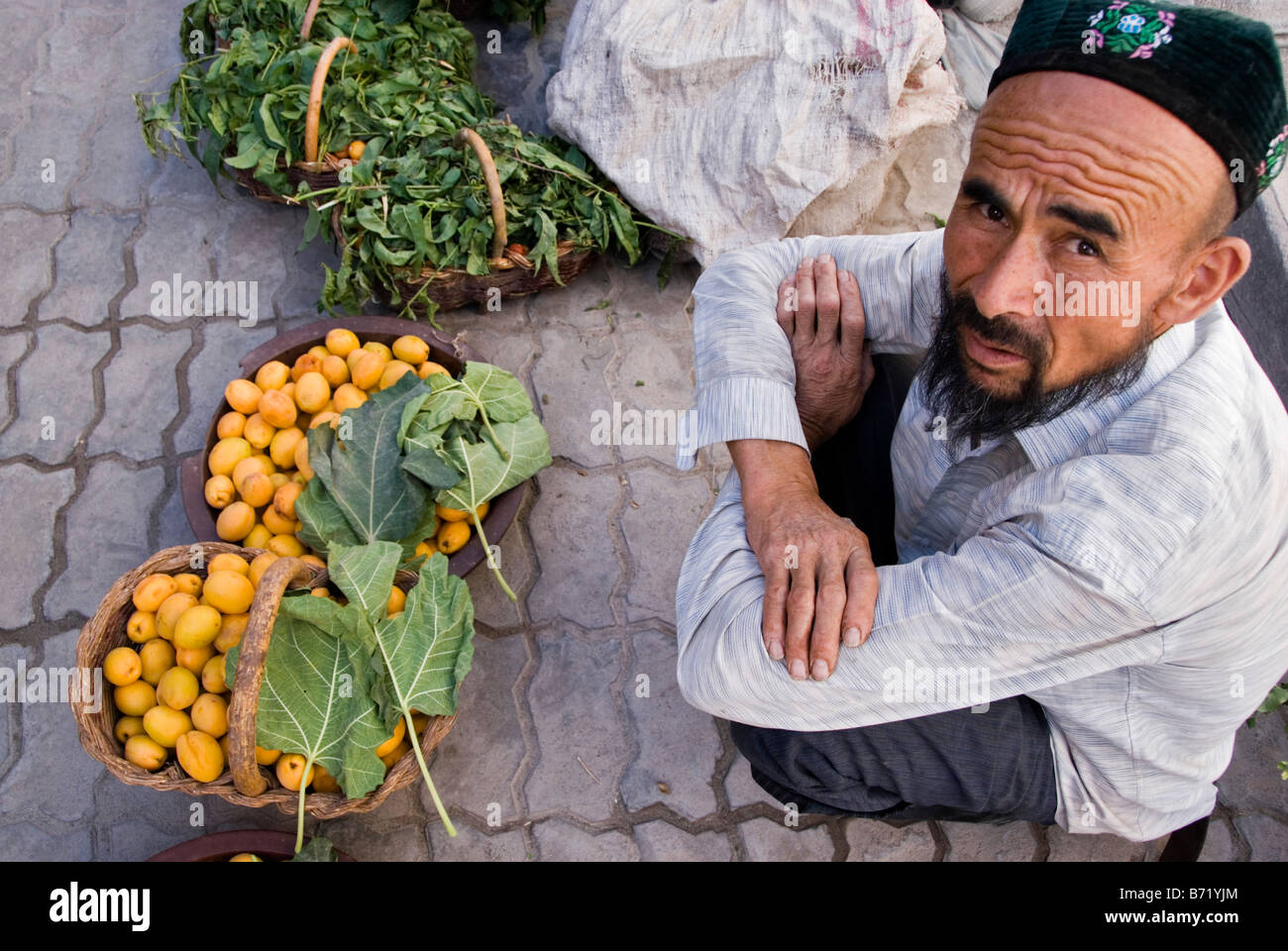 Uighur man selling fruit in the street market Kashgar Xinjiang China Stock Photo