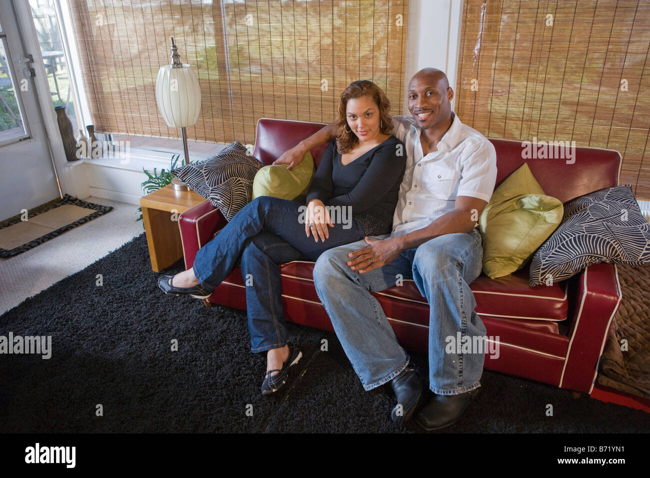 Happy African American couple sitting on living room couch Stock Photo ...