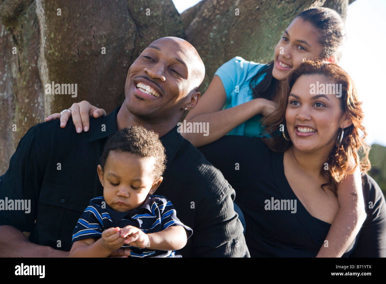 Happy African American family sitting by tree in backyard Stock Photo ...