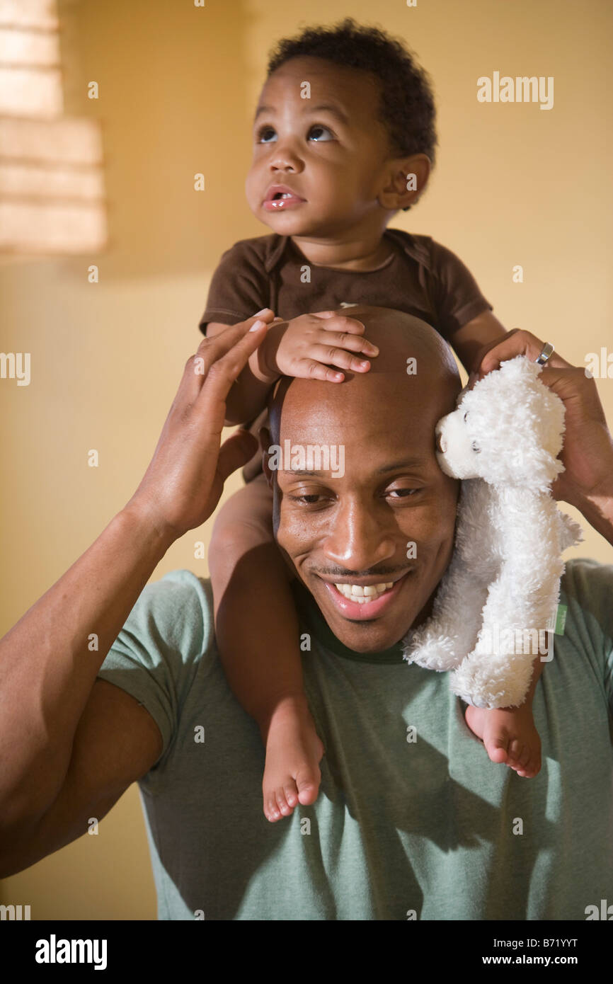 Happy African American father holding baby son on shoulders Stock Photo ...