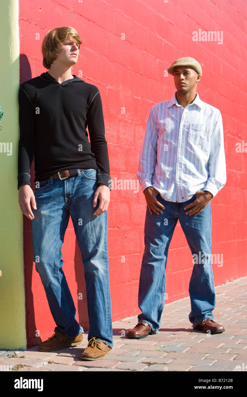 Young men standing in sunlight in front of brick wall Stock Photo - Alamy