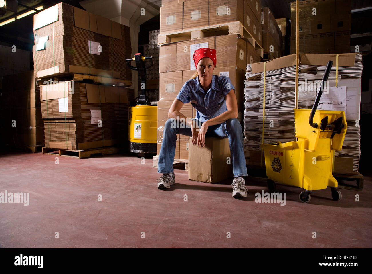 Female janitor in warehouse next to cartons Stock Photo Alamy