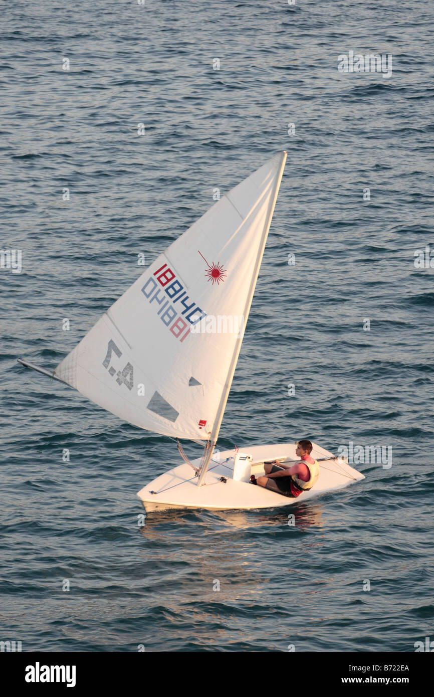 Teenage boy sailing in a dinghy bathed in warm late afternoon light at Playa San Juan Tenerife