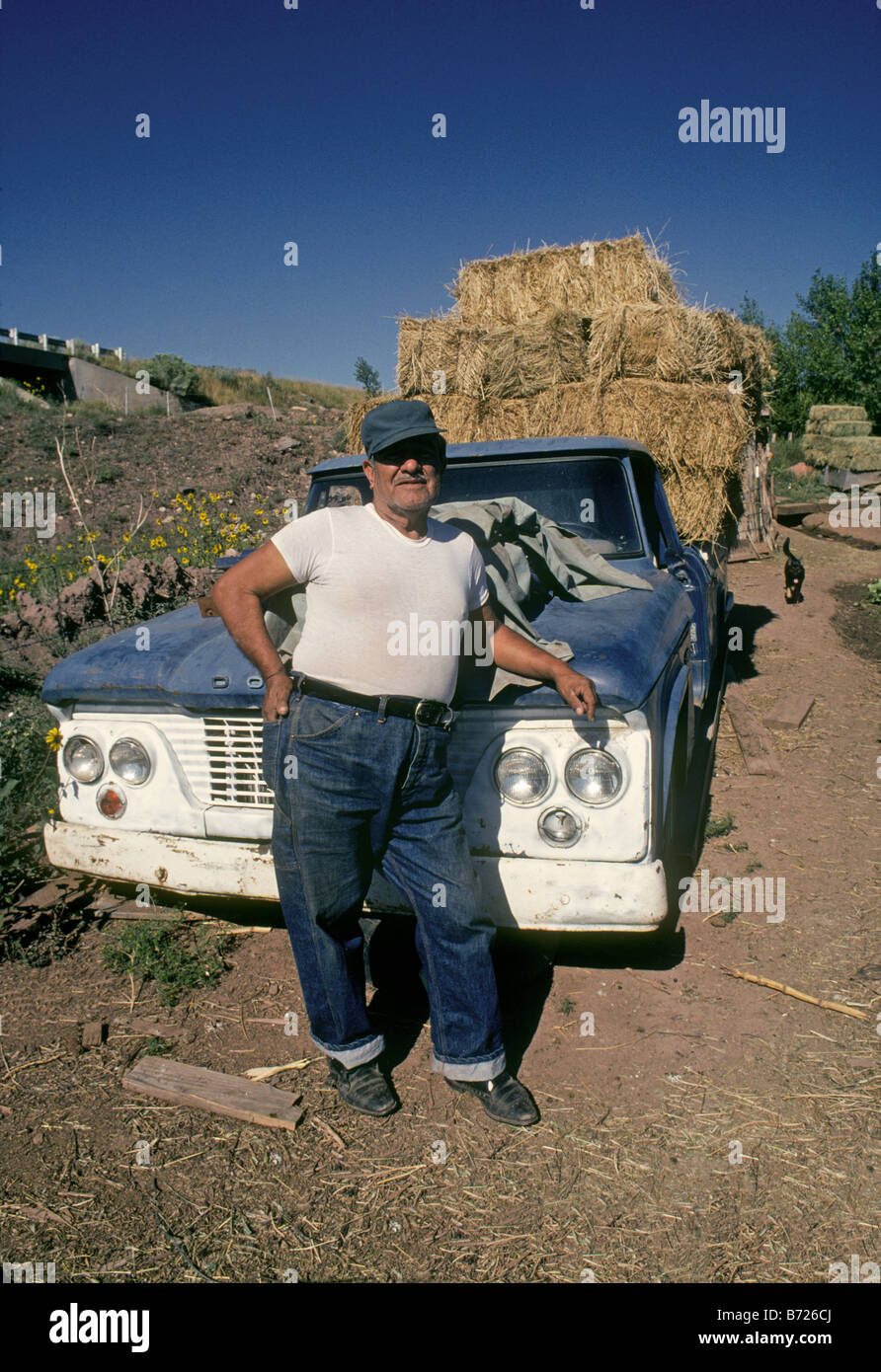 Near the tiny spanish colonial village of Gabaldon in northern New Mexico this elderly farmer leans against his ancient pickup Stock Photo
