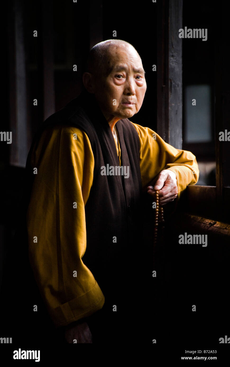 Budhist nun with a rosary looking out the window Emei Shan Sichuan China Stock Photo