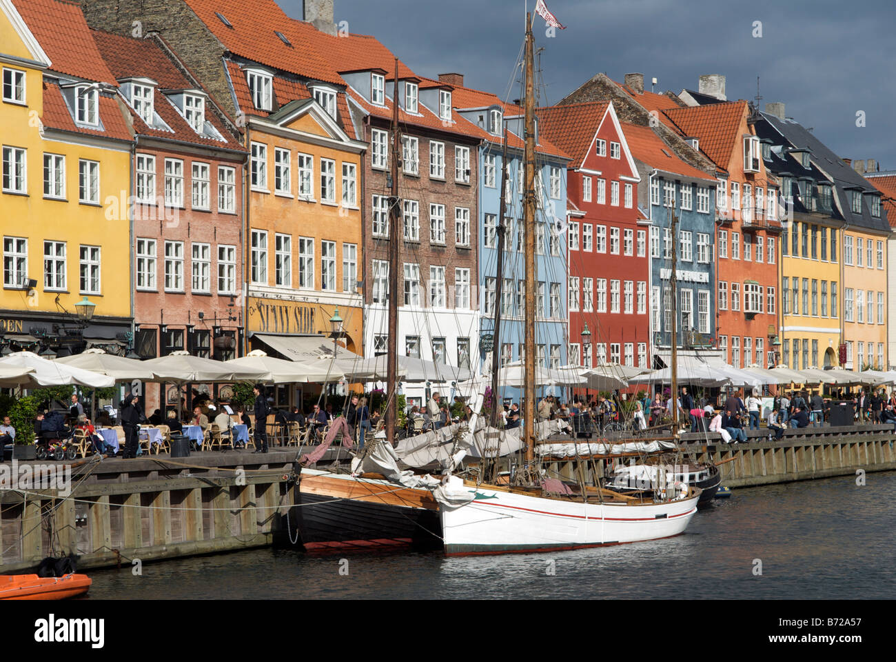 Boats and colourful buildings with waterfront cafes and restaurants Nyhavn Copenhagen Denmark Stock Photo