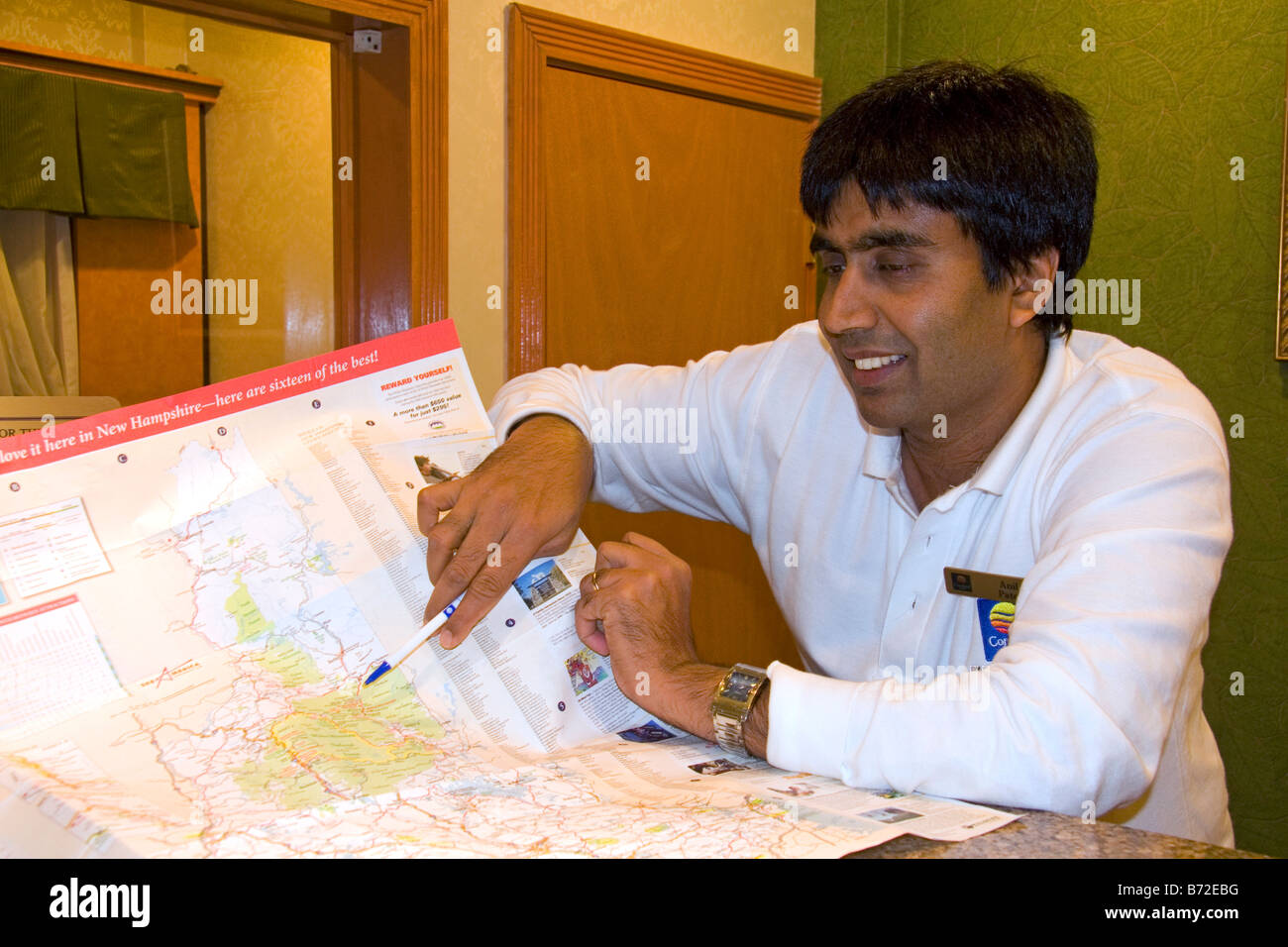 Hotel desk clerk using a map to give directions in the town of Ashland New Hampshire USA Stock Photo