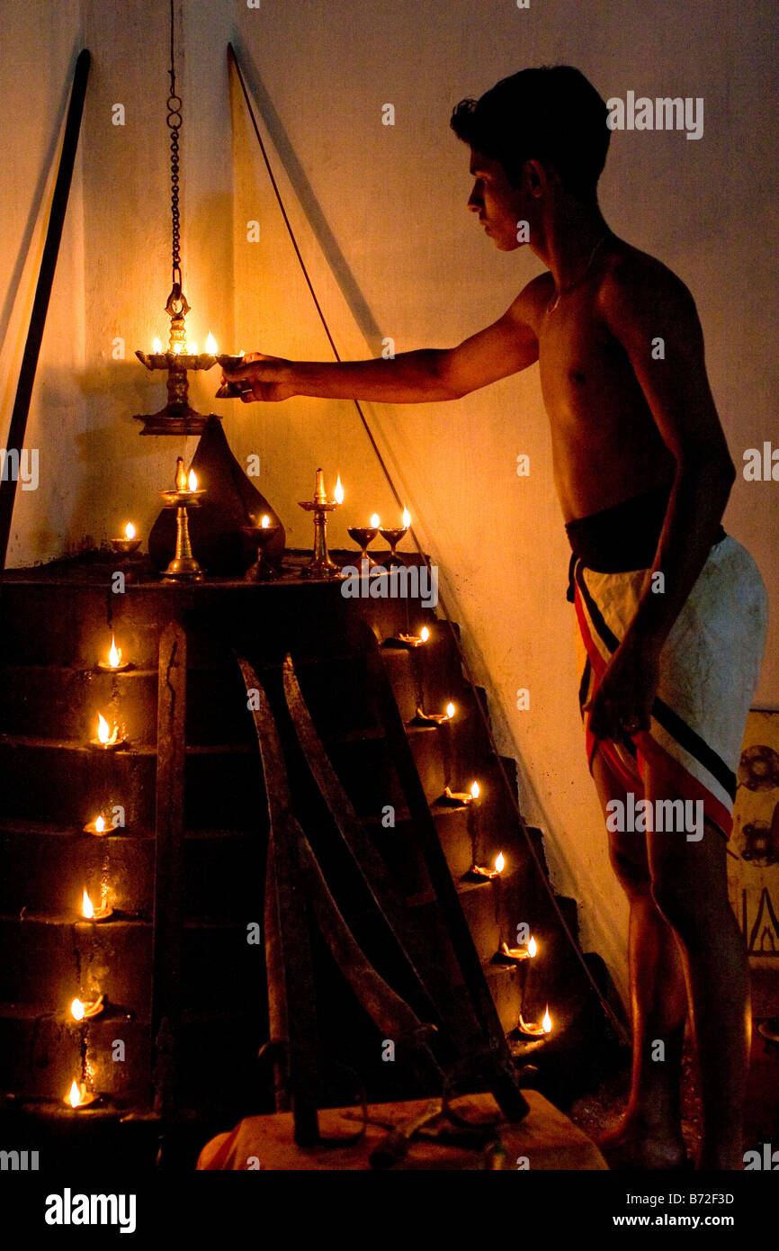 A student lights a lamp among the seven tiers (puttara) of lamps (guruthara) in the south west corner of a kalari. Stock Photo