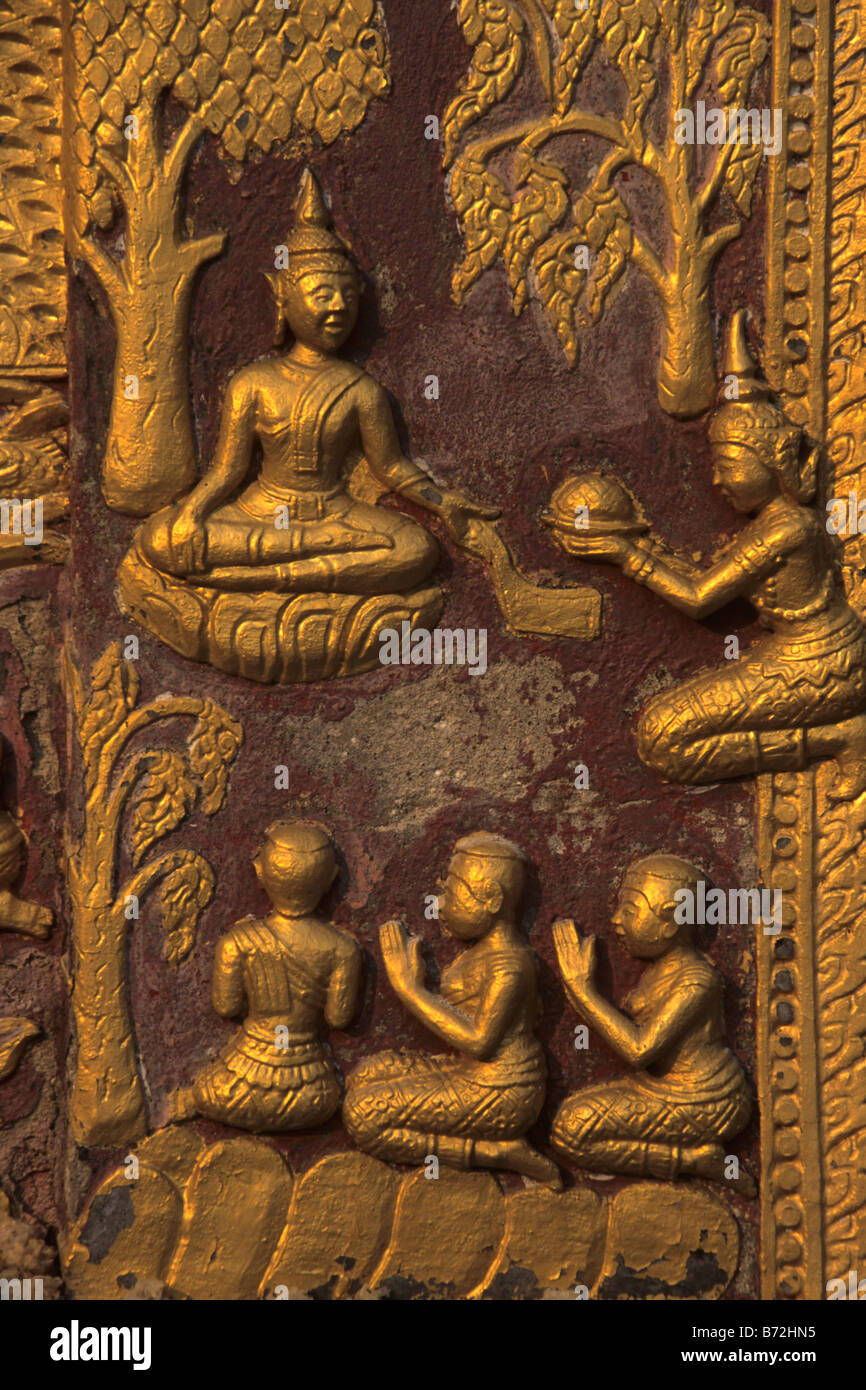 Embossed Golden Images Showing Offerings to the Buddha on the Red Chapel, Wat Xieng Thong Temple, Luang Prabang, Laos Stock Photo