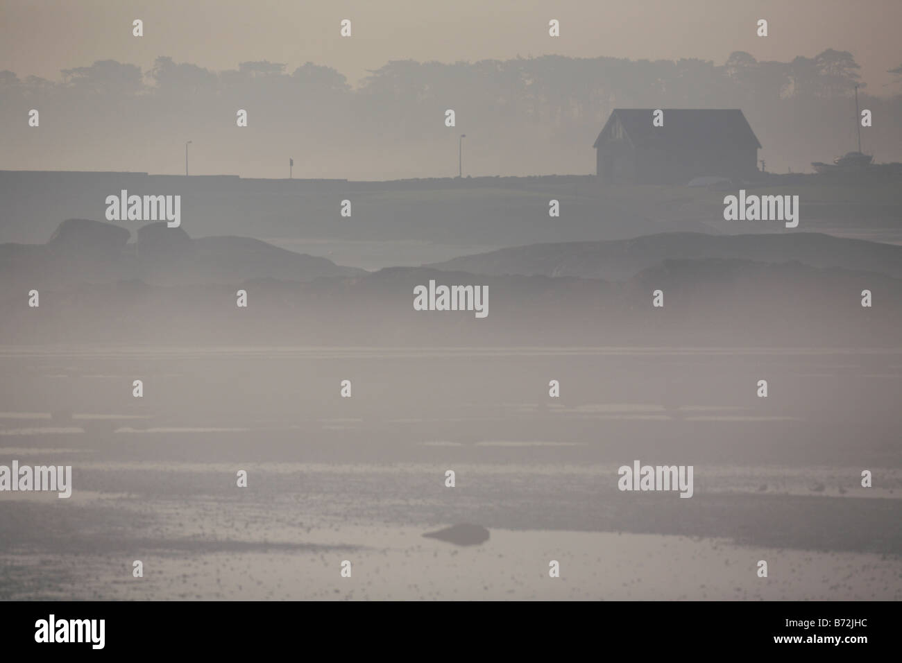 view of boathouse across bay with tide out on misty foggy morning in county down Northern Ireland UK Stock Photo