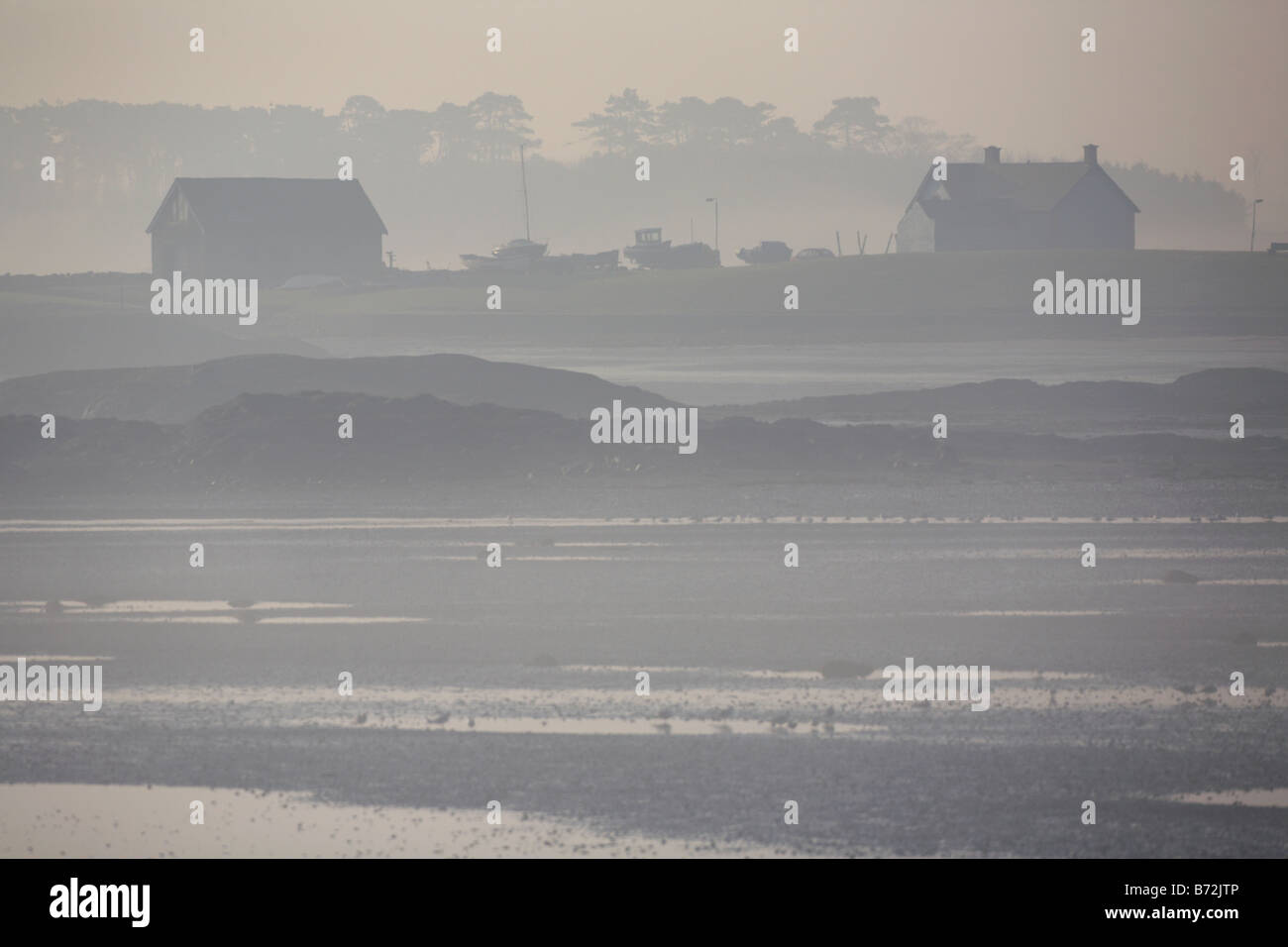 view of house and boathouse across bay with tide out on misty foggy morning near groomsport in county down Northern Ireland UK Stock Photo