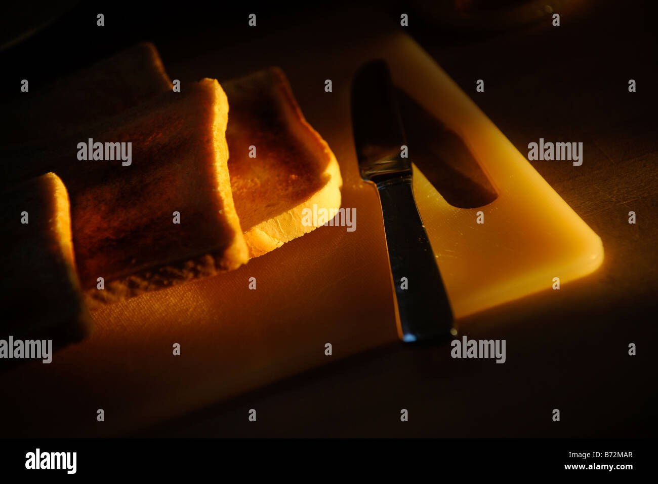 Slices of toast on a bread board lit by early morning sunshine. Picture by Jim Holden. Stock Photo