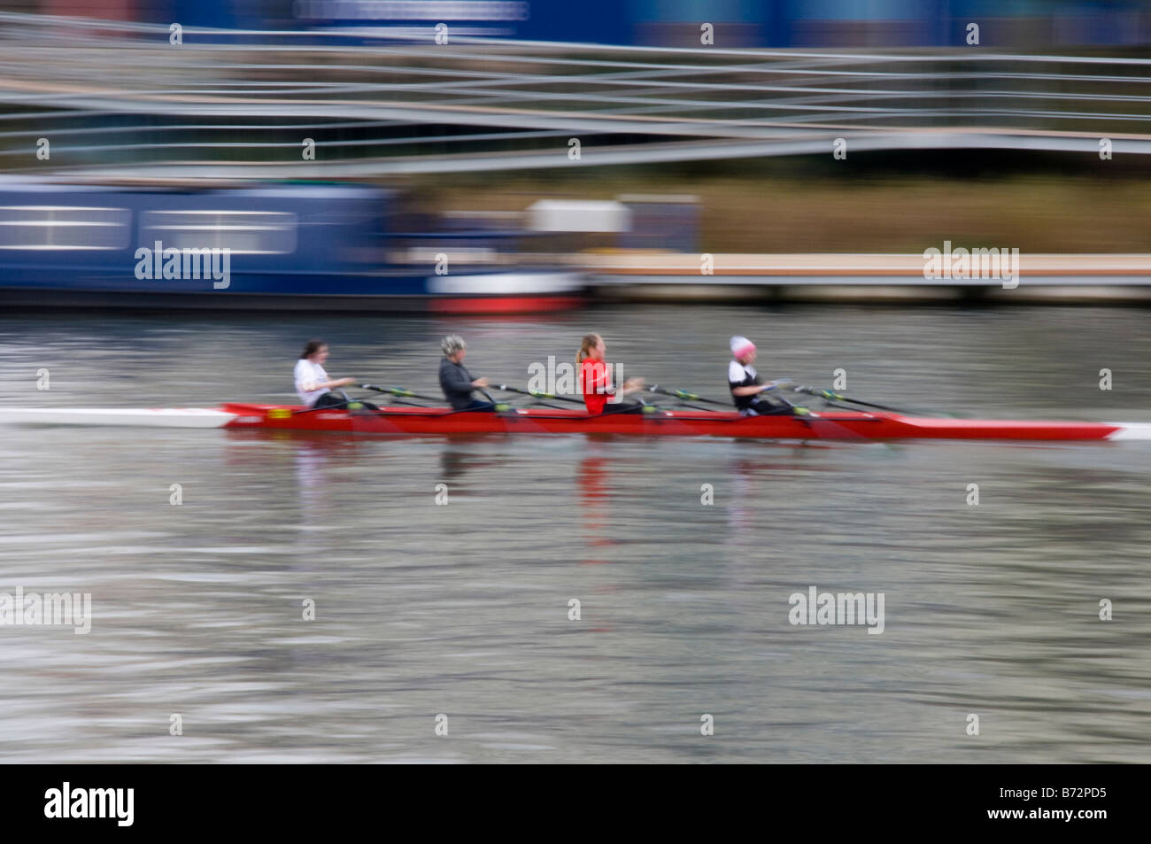 Motion blurred rowers in a red rowing boat training on a winters day