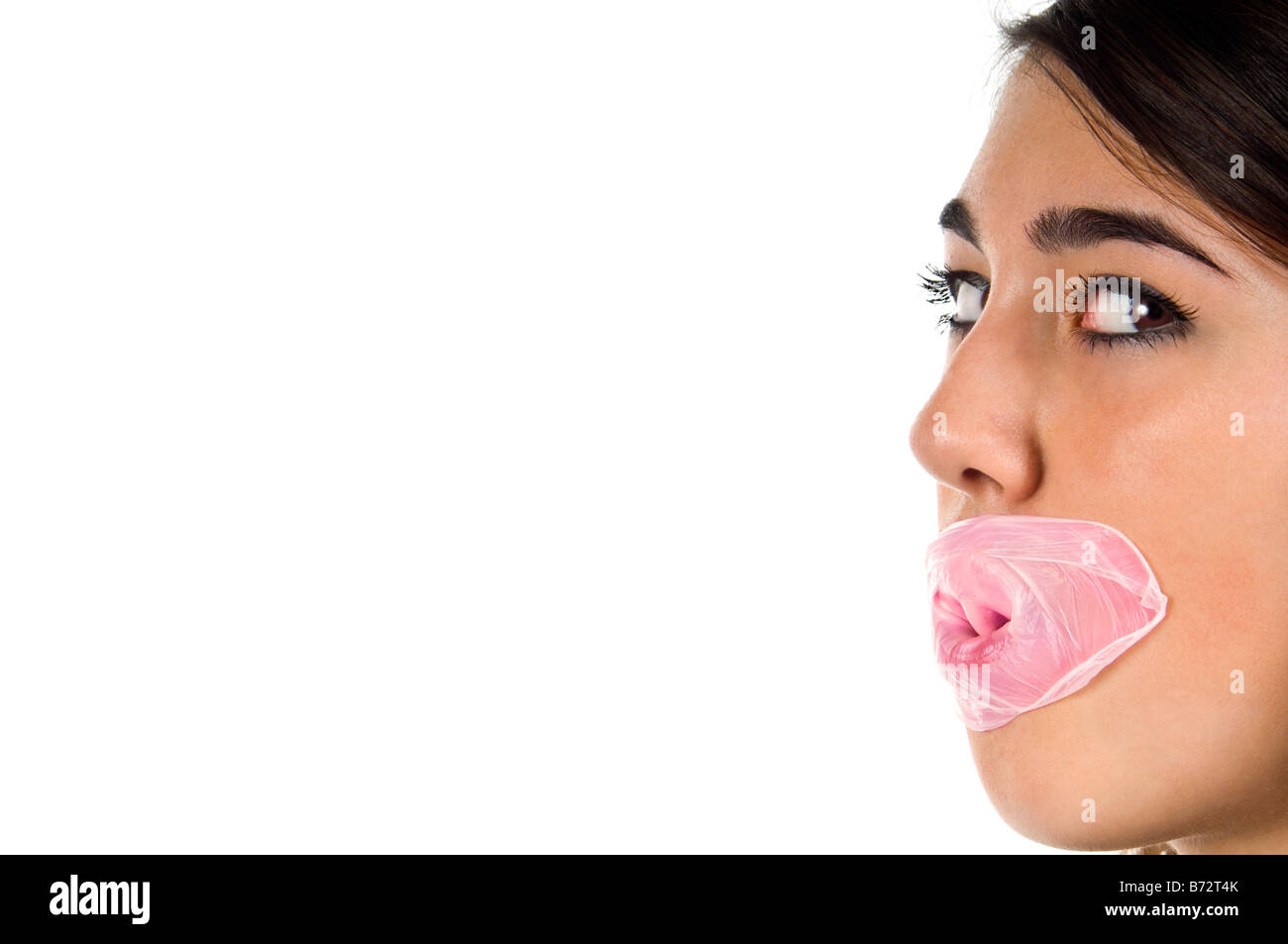 Horizontal close up portrait of a young teenage girl with pink bubblegum burst all over her face against a white background Stock Photo
