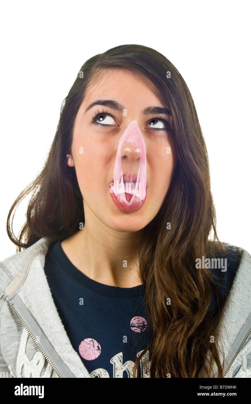 Vertical close up portrait of a young teenage girl with pink bubblegum all over her nose and face against a white background Stock Photo