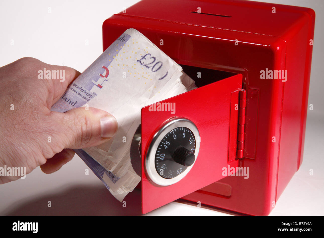 red safe cash money combination credit crunch keeping box bank saving rainy day save hide tax deposit pound £ currency Stock Photo