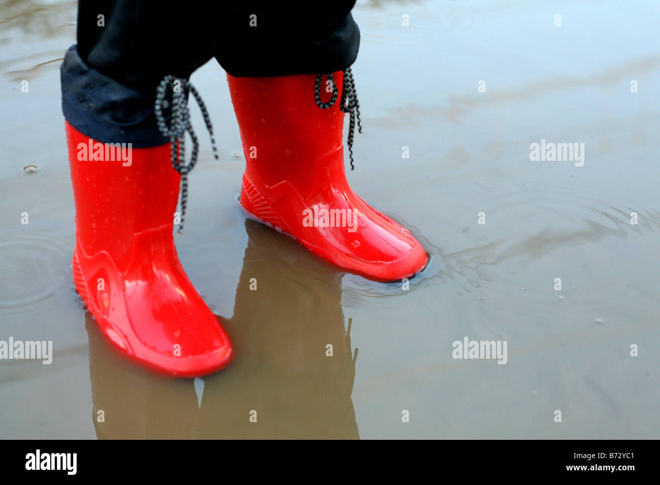 a child in red wellington boots playing in puddles Stock Photo - Alamy