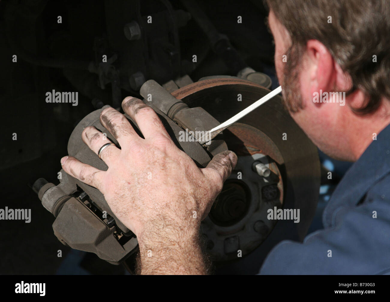 An auto mechanic removing the brake housing from a front disc brake