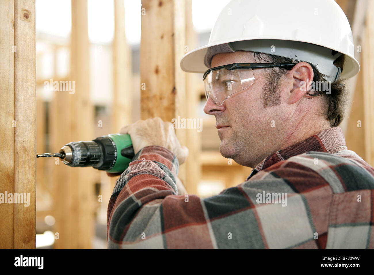 A construction worker drilling and wearing proper safety equipment ...