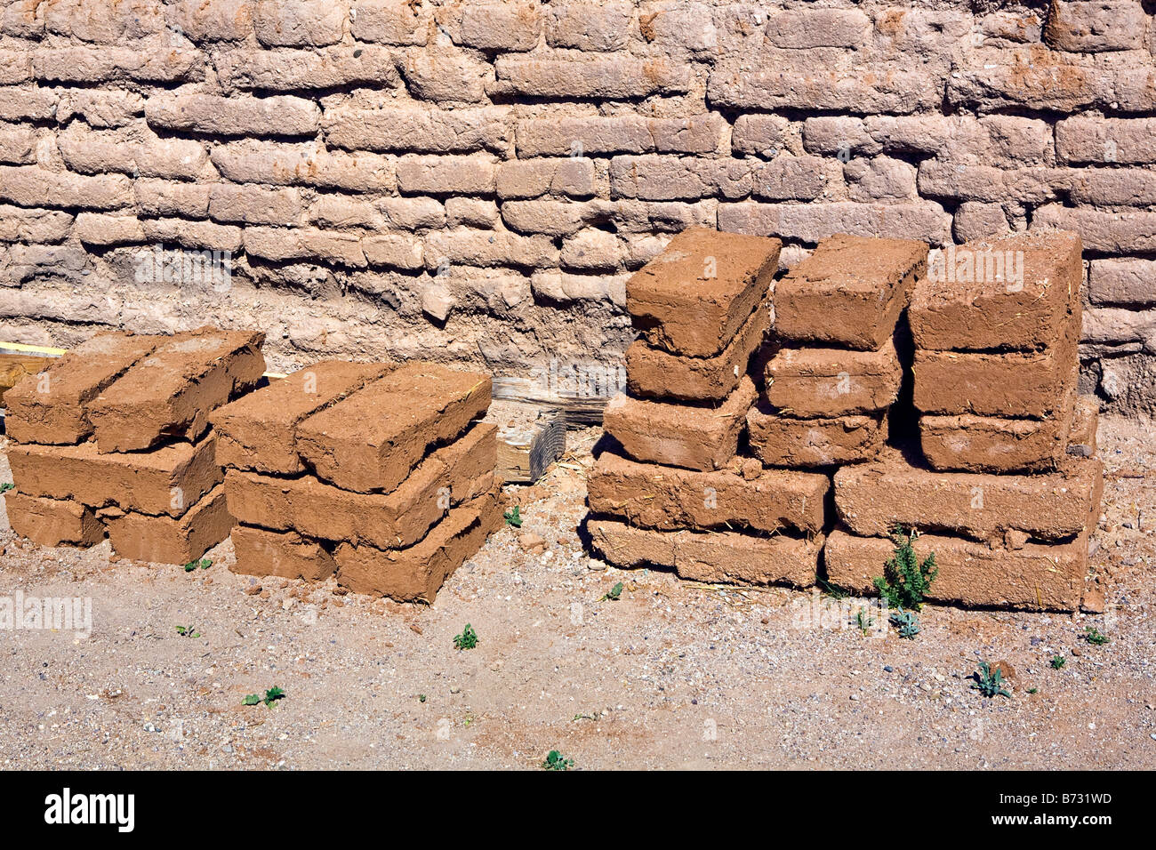 Image of traditional adobe bricks stacked and drying against an adobe brick wall in the sun Stock Photo