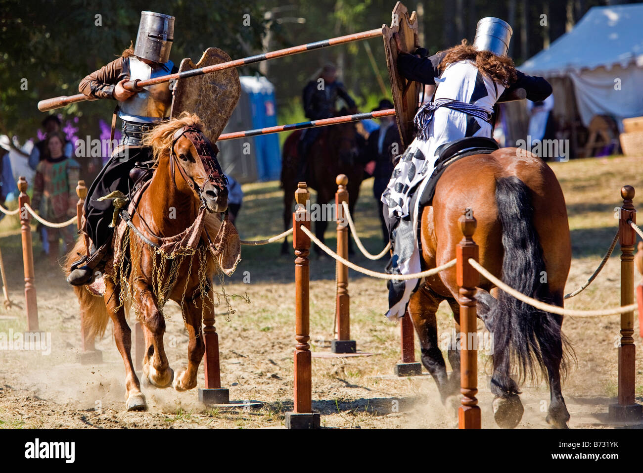 Image of two men dressed in Medieval style clothing riding a horses and carrying a lance in a jousting tournament Stock Photo