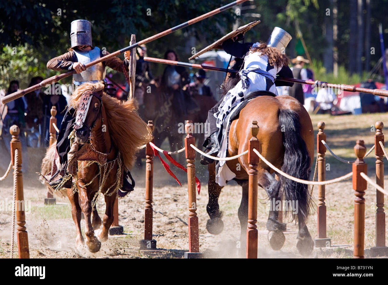 Image of two men dressed in Medieval style clothing riding a horse and carrying a lance in a jousting tournament Stock Photo