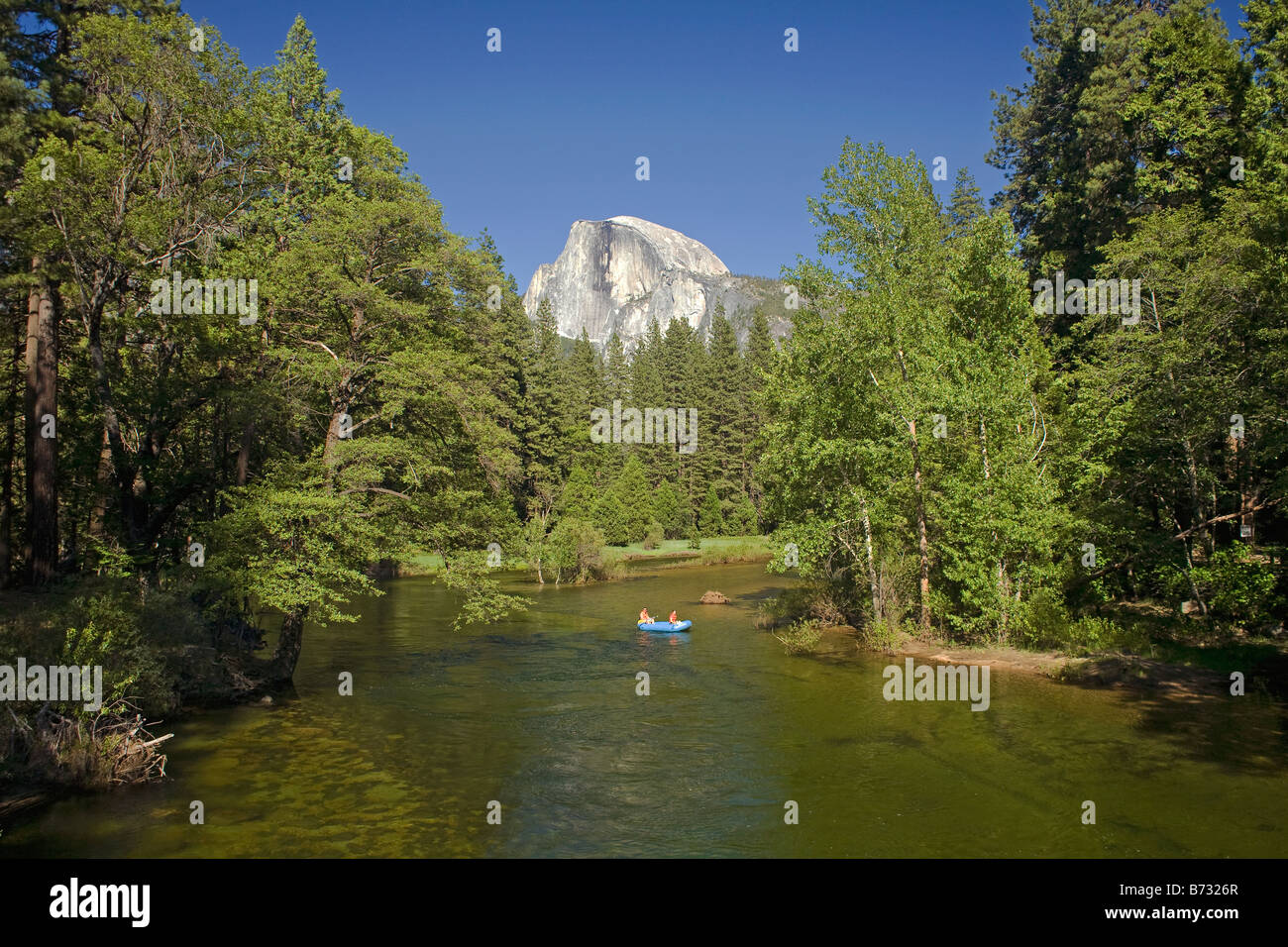 CALIFORNIA - Half Dome towering over the rafters floating down the Merced River in Yosemite Valley;  Yosemite National Park. Stock Photo