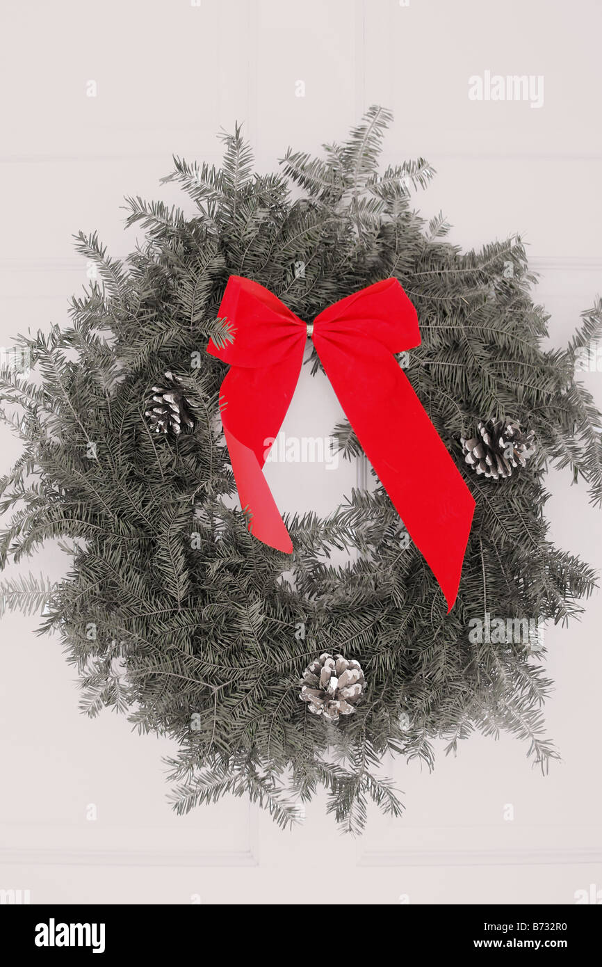 A Christmas wreath hanging on the white front door of a home Red bow Stock Photo