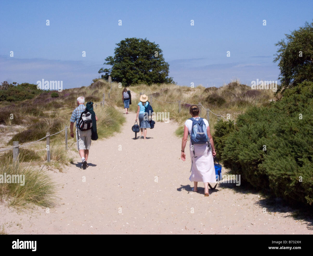 people walking over dunes Knoll Beach Studland Dorset Stock Photo
