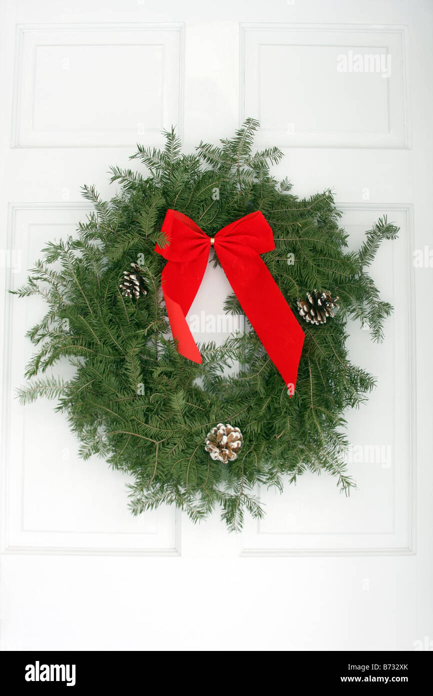 A Christmas wreath hanging on the white front door of a home Stock Photo