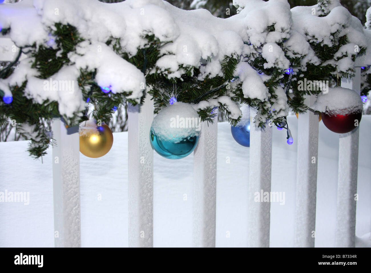 A porch with Christmas decorations lights and ornaments covered in snow Stock Photo