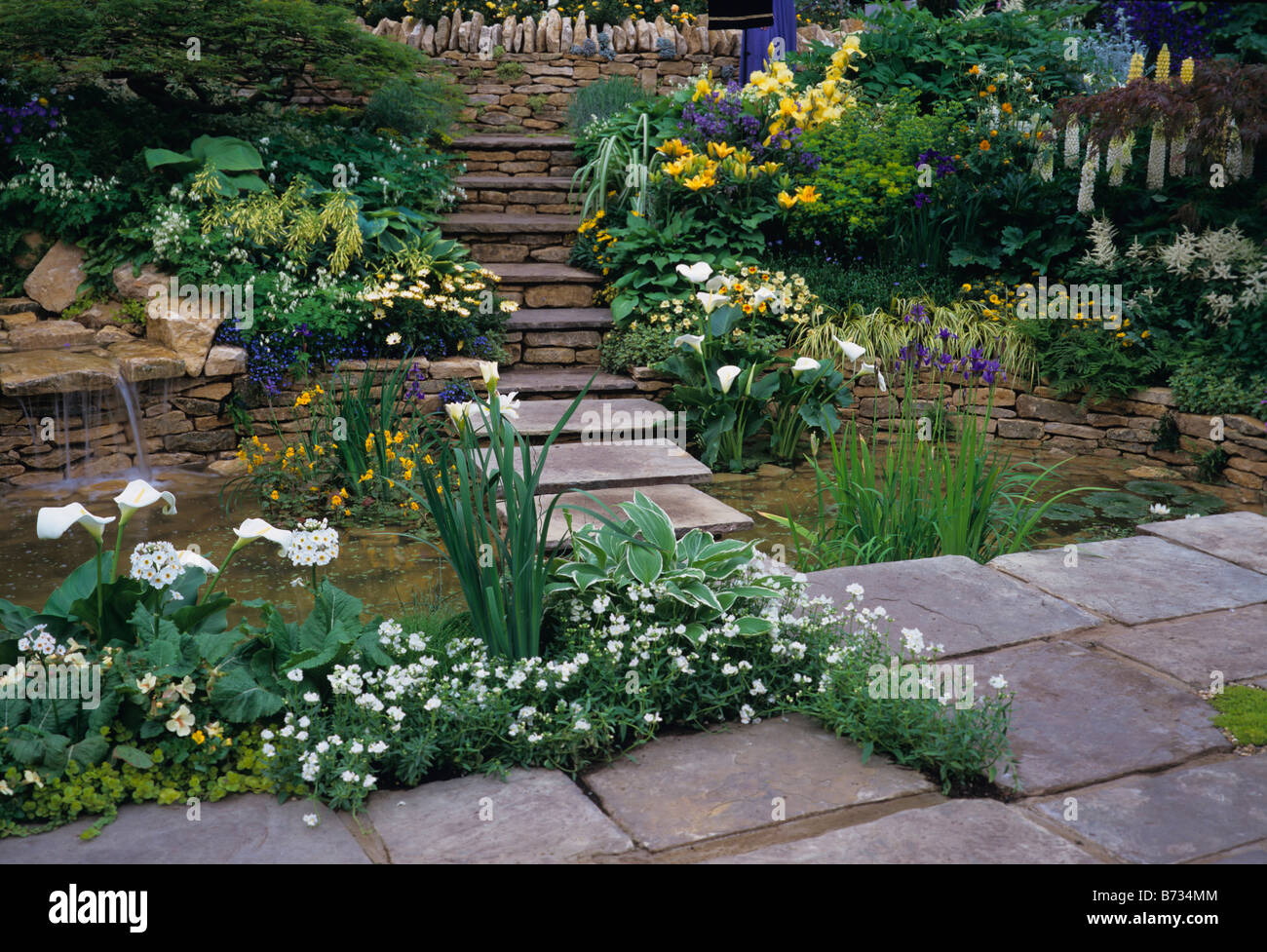 Flagstone steps over pool with mixed herbaceous planting Stock Photo
