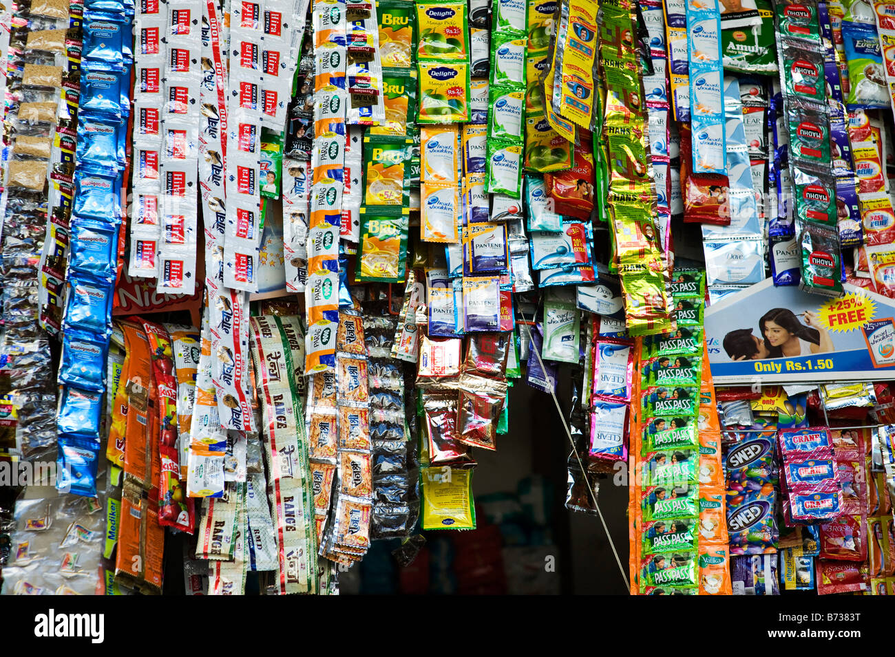 Single use sweet and consumer item packets hanging in an rural Indian shop stall. Andhra Pradesh, India Stock Photo