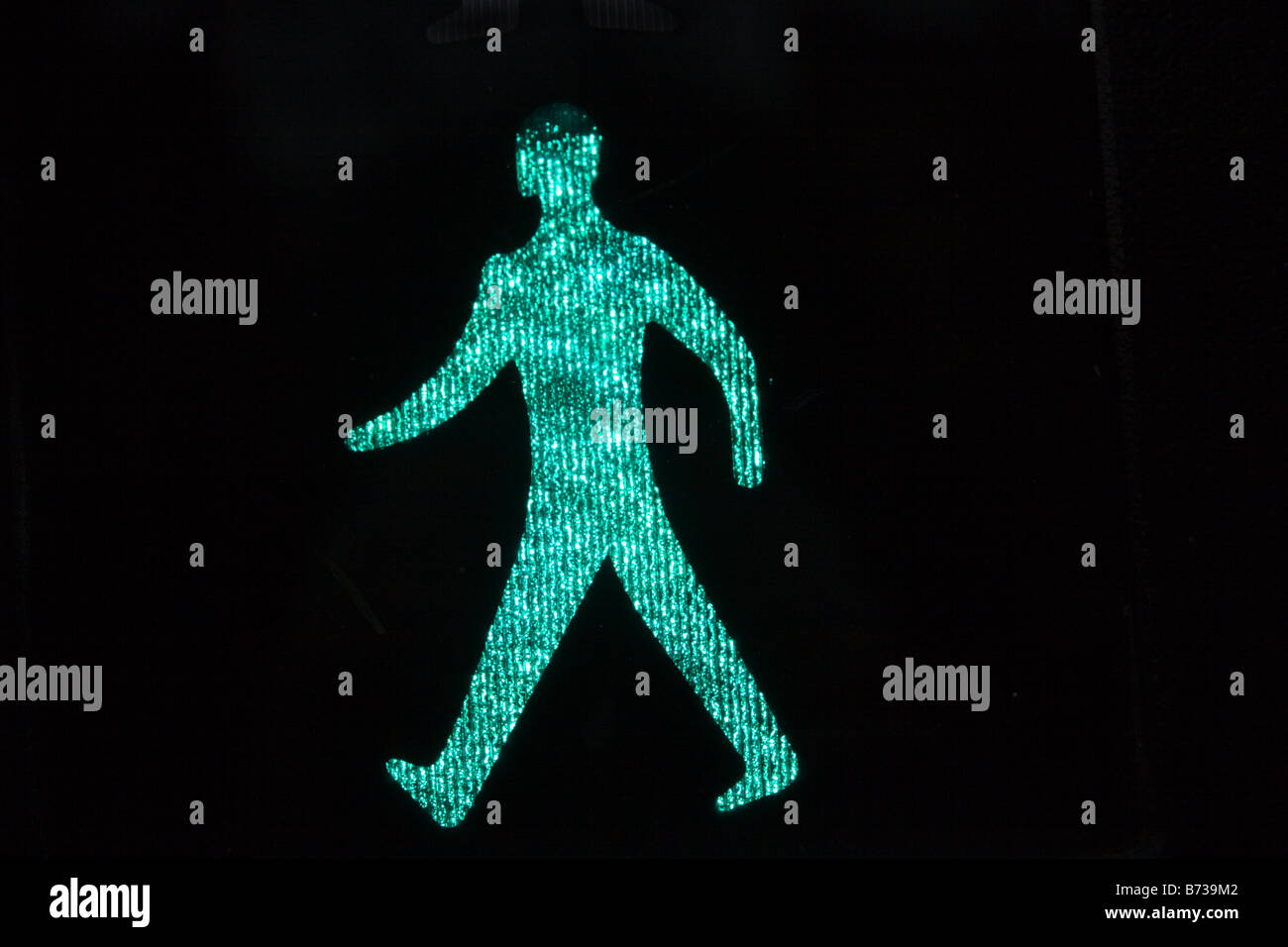 An illuminated Green Man 'Go' sign at a pedestrian crossing. Stock Photo